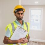 Specialist in hard hat and safety vest holding a clipboard