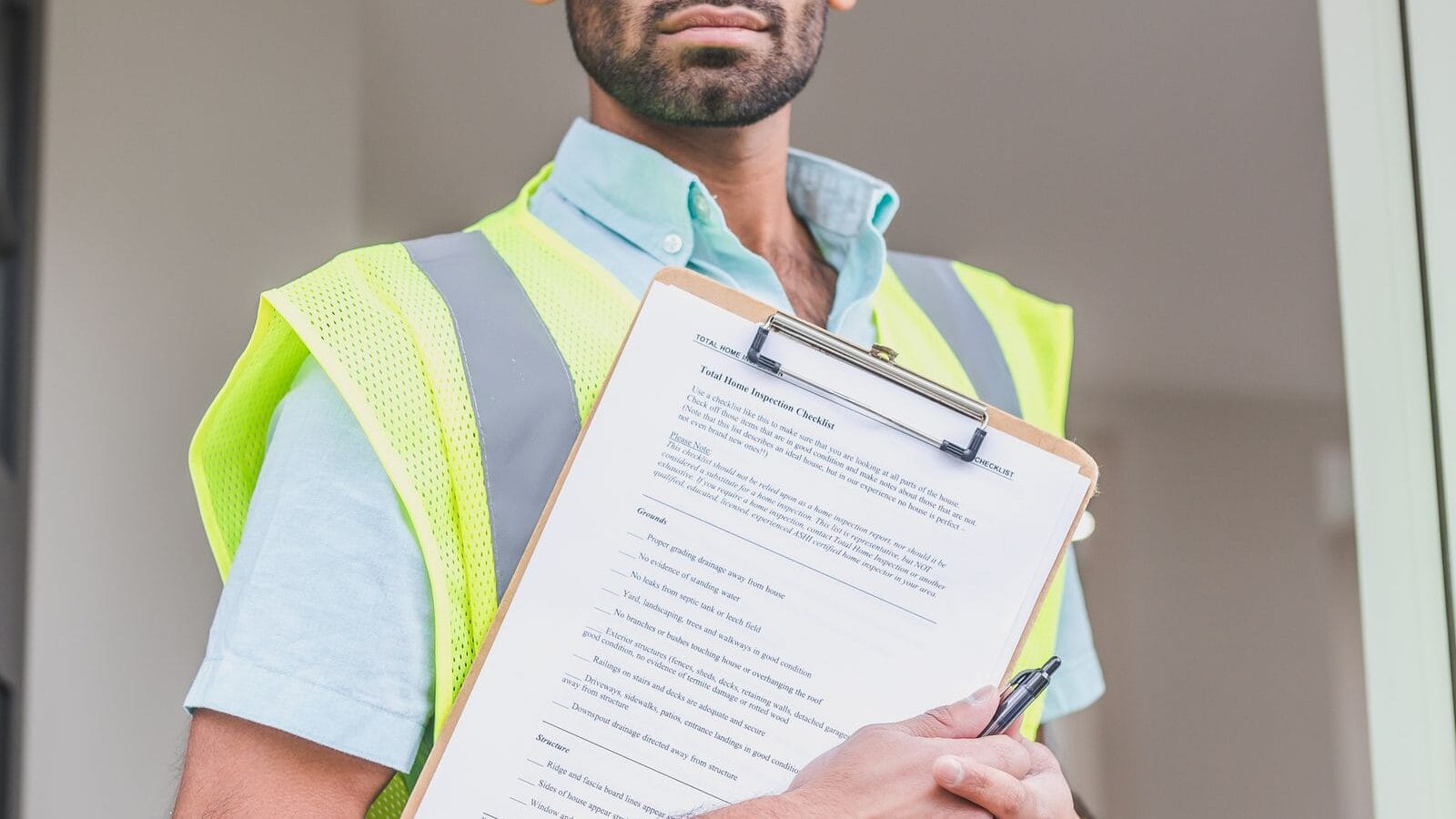 Engineer in hard hat and safety vest reviewing technical documents on a clipboard